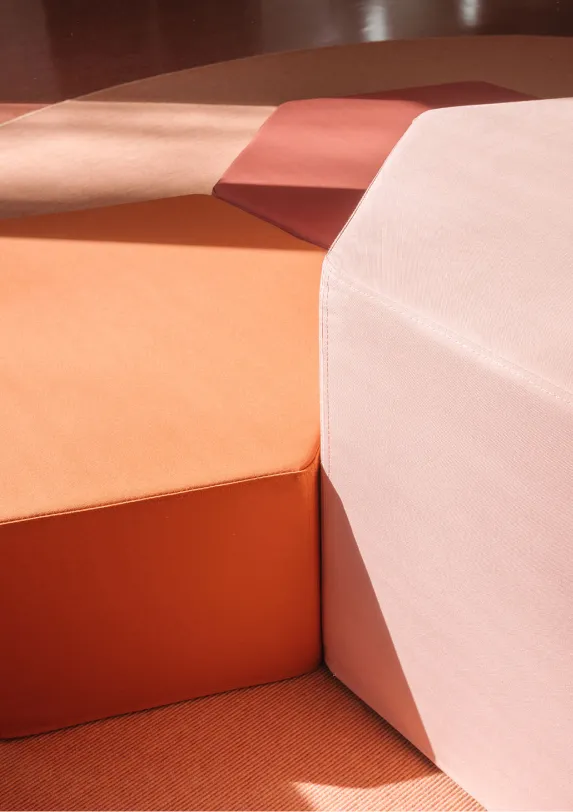 Modulare Polster-Podestlandschaft in Rosé- und Terrakottatönen – Papoq Kita-Möbel Nahaufnahme mehrerer polygonaler Sitzpolster in abgestuften Rosé-, Orange- und Terrakottatönen, kombiniert zu einer modularen Podestlandschaft