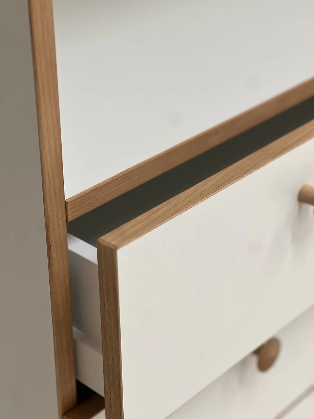 Detailaufnahme einer weißen Schublade mit Buchenholzrahmen und rundem Holzknauf – Kita-Möbel von Papoq